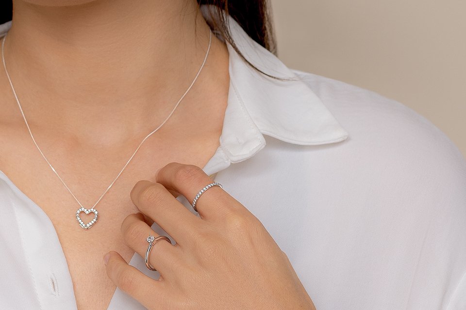 An close up image of a woman wearing Pure Brilliance lab grown diamond necklace and ring. 