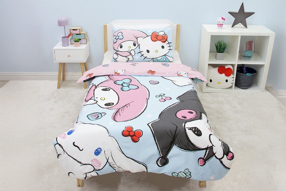 A bed made with a Hello Kitty and Friends panel pink single bedding set.