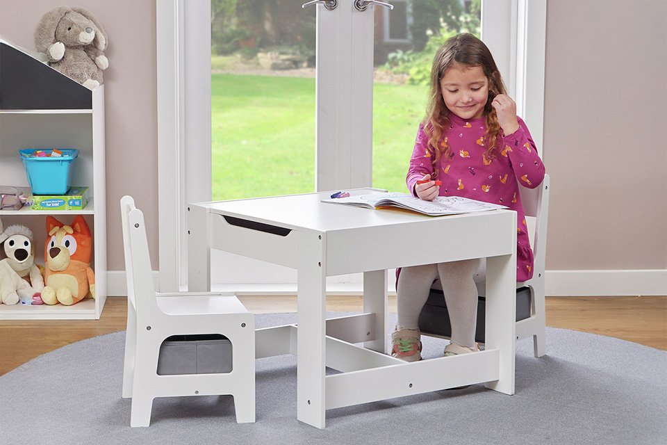 A child sitting at a Liberty House kids' activity table with 2 chairs. 