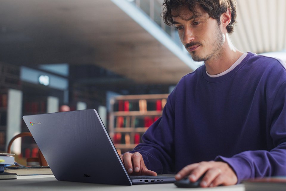 A man wearing purple T-shirt using ASUS CX1405CTA 14in i3 8GB 12GB Chromebook Plus.