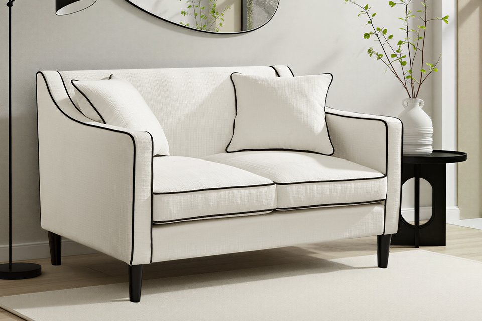 A white two seater sofa with black borders in a living room.