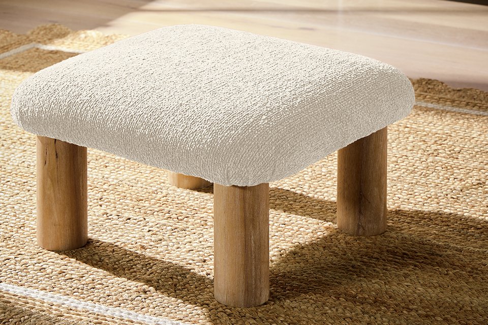 A boucle footstool on a rug.