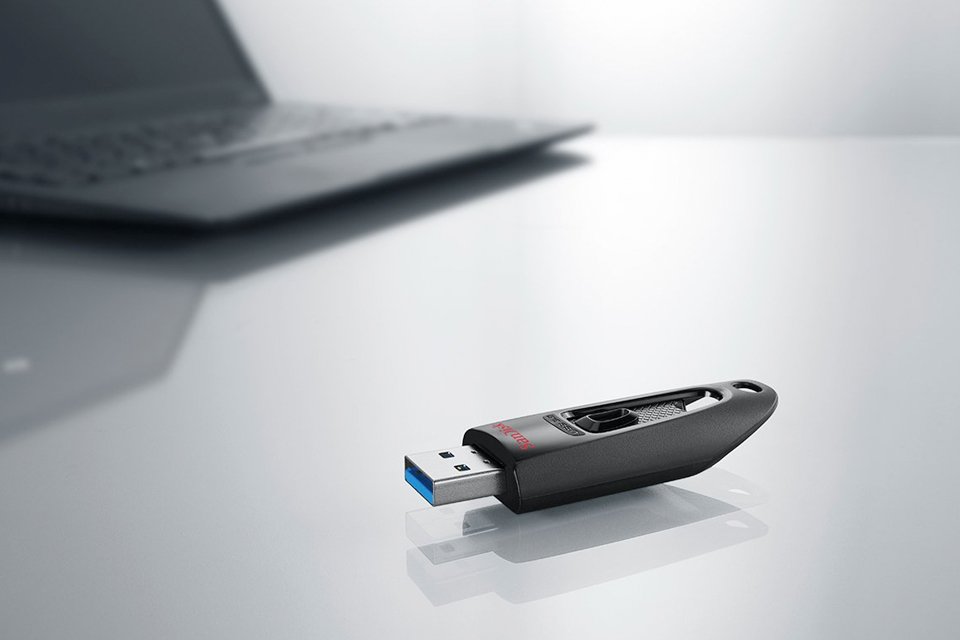 A USB drive kept on a table in front of a laptop.