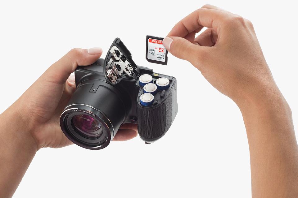 Photographer putting a SD memory card into a DSLR camera. 