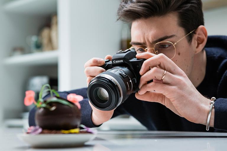 Man taking a photograph with a Canon EOS M50 MK II Mirrorless camera.
