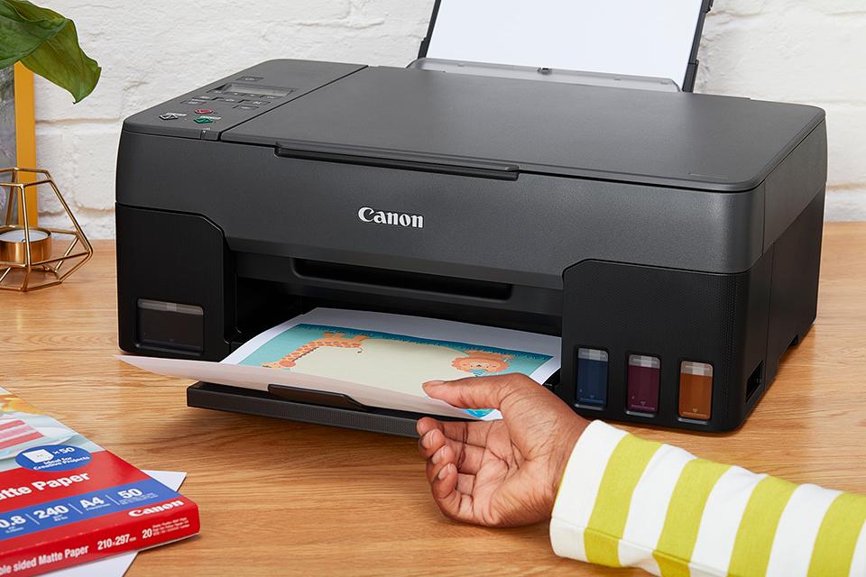 Person taking a print from a Canon MegaTank Printer tray.