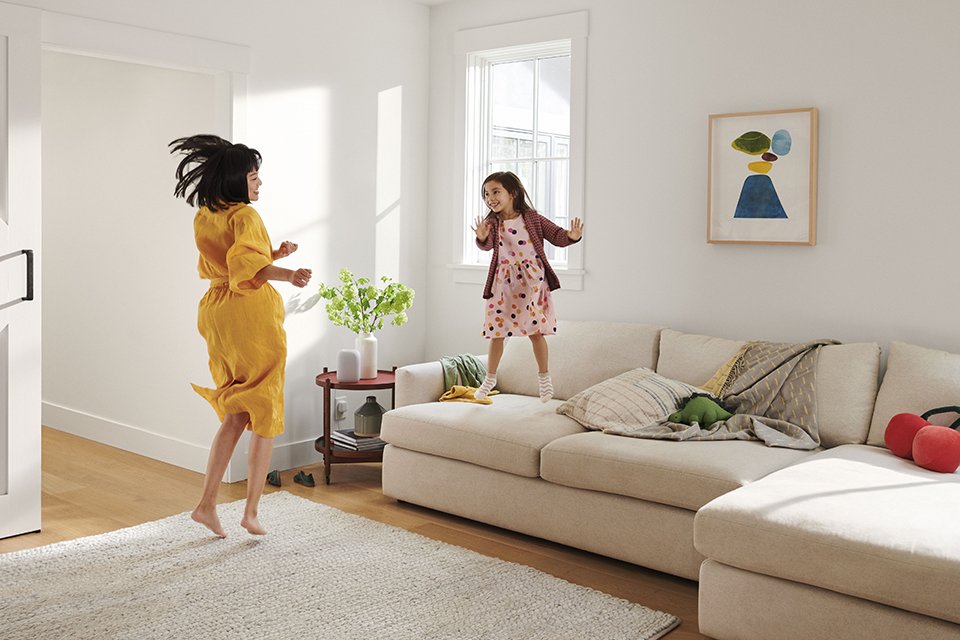 A family dancing to music from a Google Nest smart speaker in their living room.