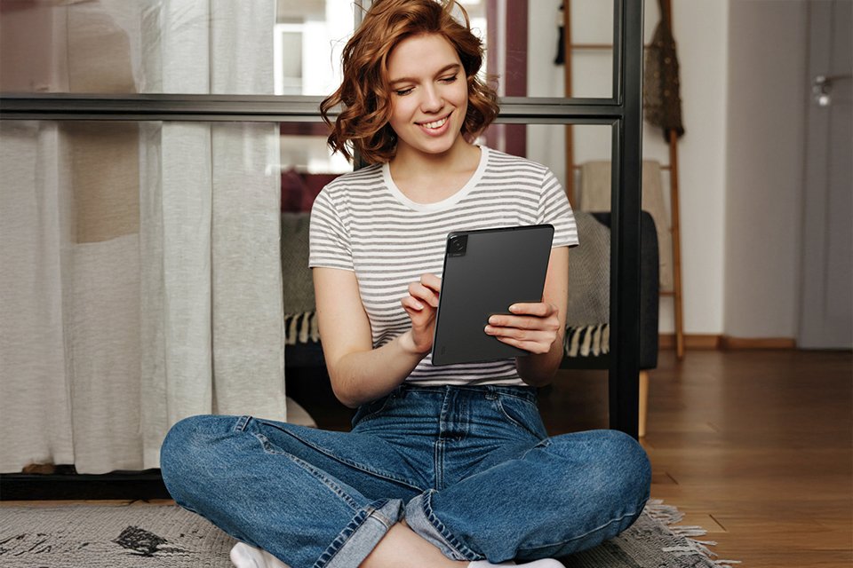 A woman scrolling through something a black TCL Tab 10L Gen 2 10.1 inch 32GB Wi-Fi tablet.