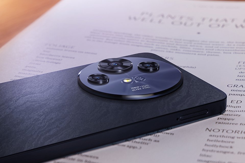 A grey TCL Pro NEXTPAPER 5G smartphone displayed upside down on a paper placed on desk.