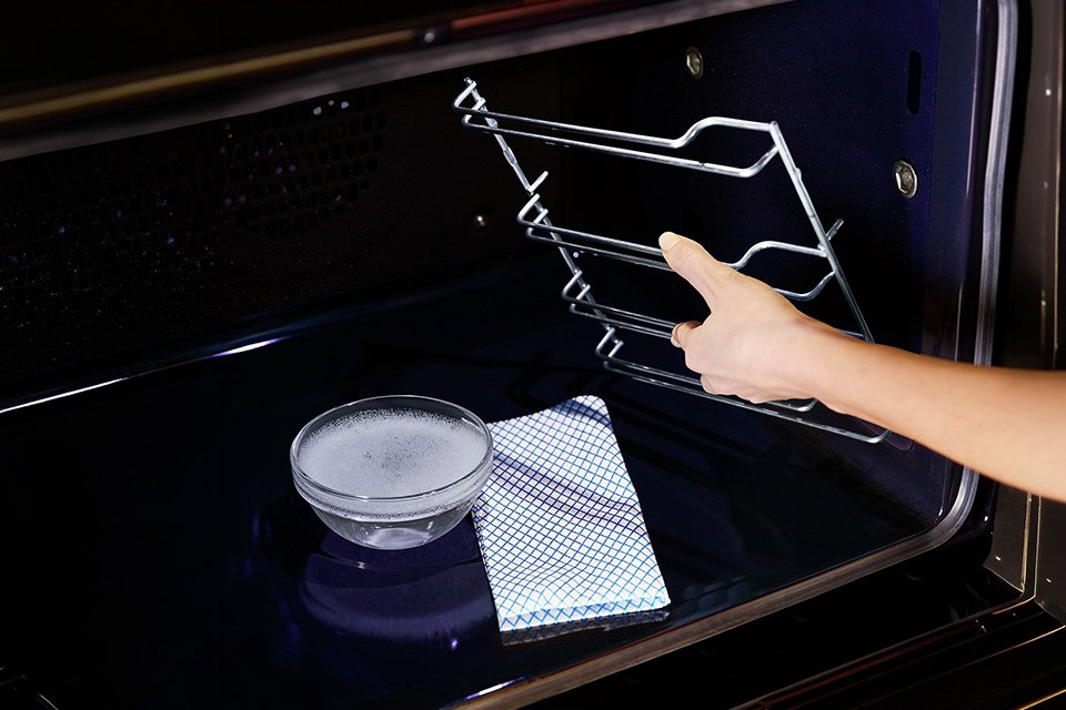 A person cleaning a Neff built-in single electric oven.
