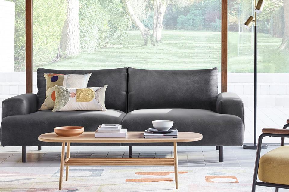 Sofa in a living room with an armchair, coffee table, and rug.