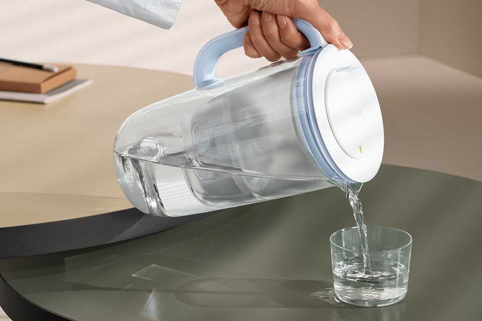 A BRITA glass jug pouring filtered water into a glass.
