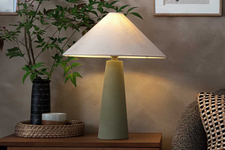 Green lamp with white light shade in living room.