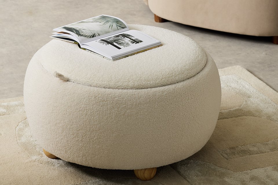 An open magazine on a Habitat Adeline Round Coffee Table - Cream.