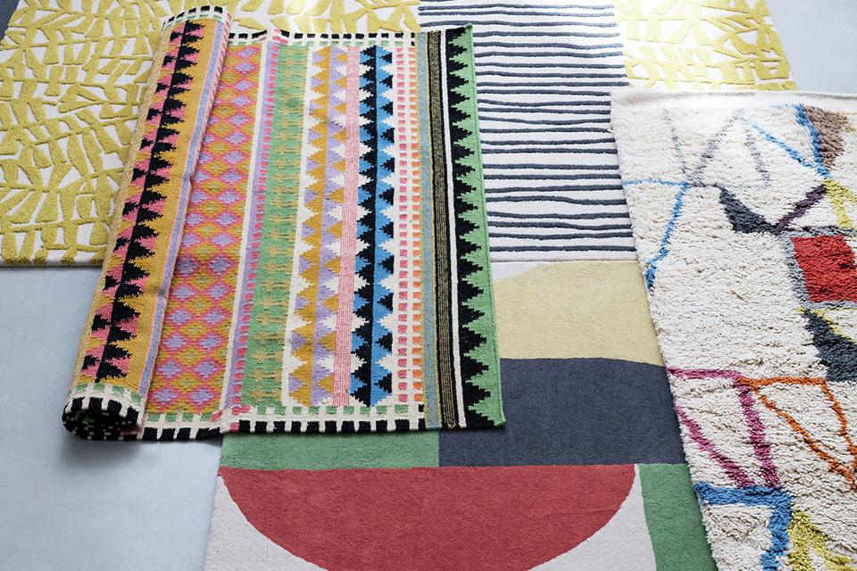 A collection of pattered 100% wool rugs on the floor.