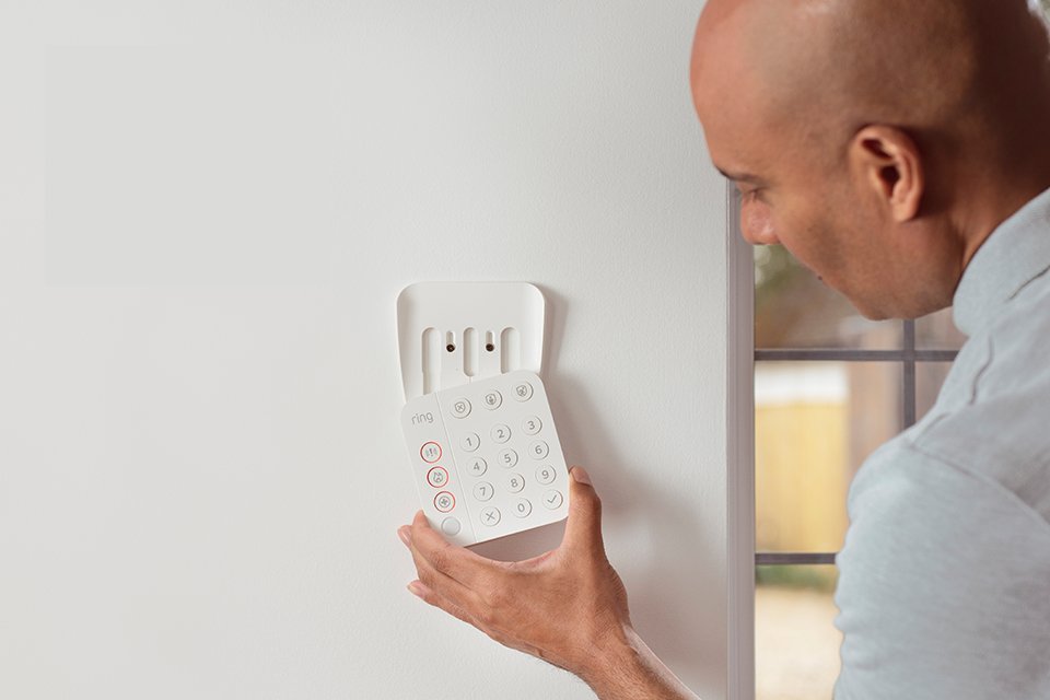  Man fitting a Ring Alarm to an internal wall.