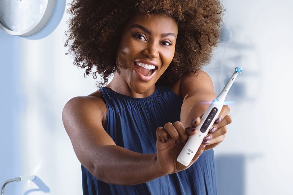 A woman holding a white Oral-B electric toothbrush.