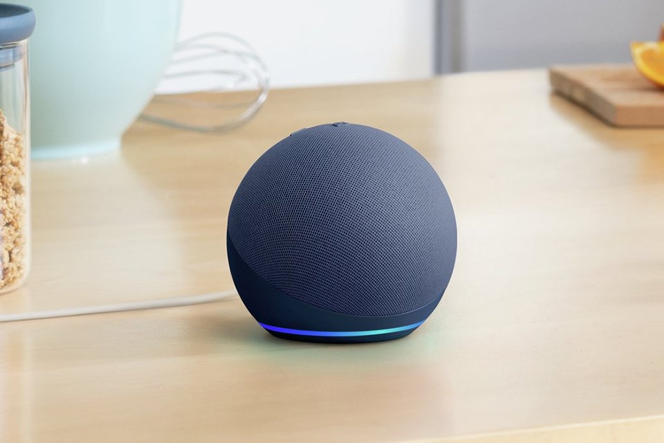 An Amazon Echo Dot 5 speaker in black on a kitchen table.