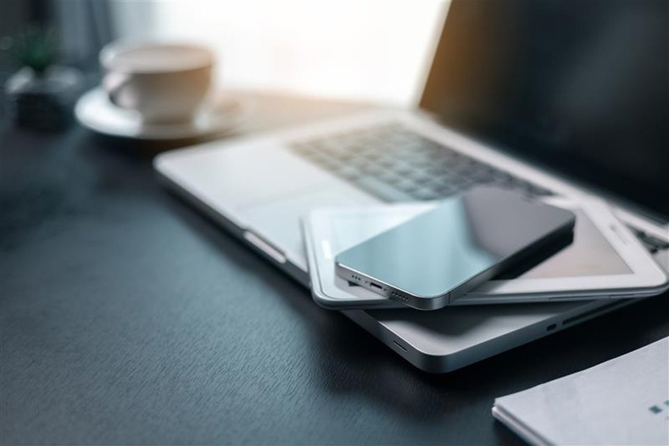 An iphone and iPad stacked on a laptop.