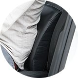 A man sitting on a chair using a support cushion.