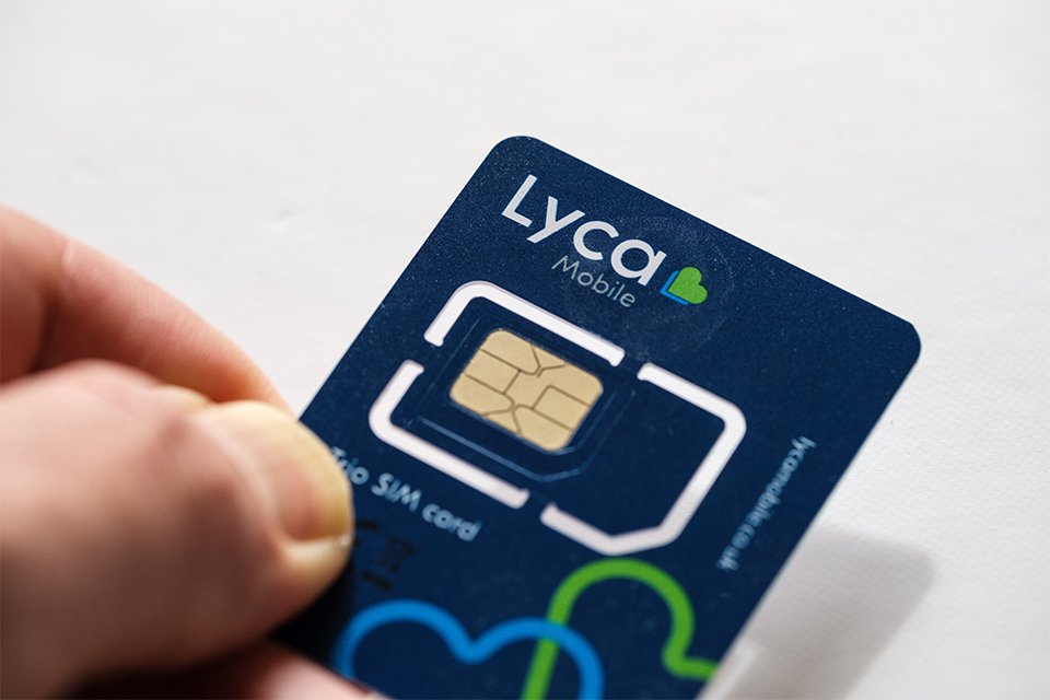 A person holding a Lyca pay as you go SIM card in their hand.