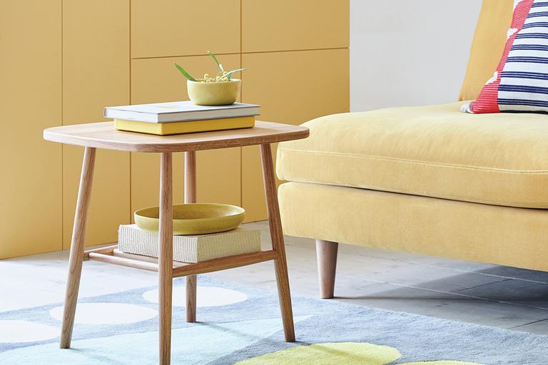 An oak side table placed in front of a sofa.