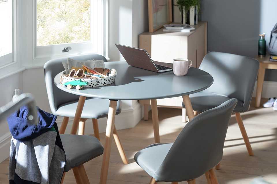 Grey dining table and chairs with splayed light wood legs.