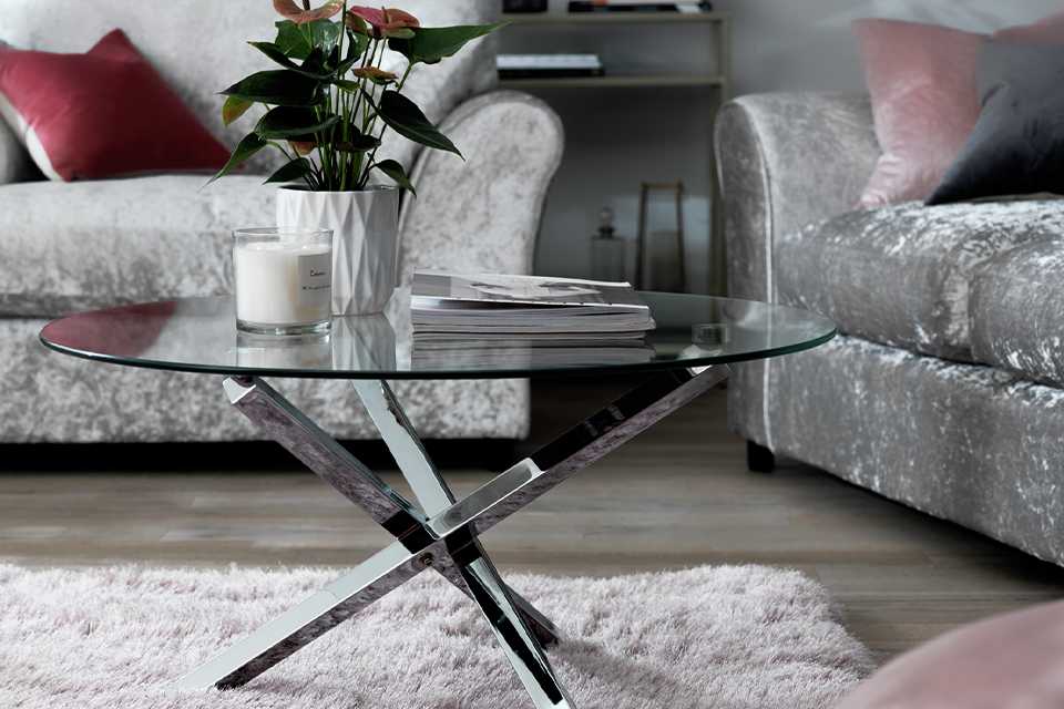 Round glass coffee table with chrome criss cross legs.