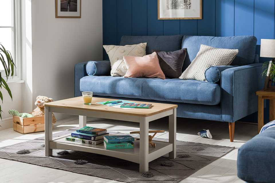 Grey, rectangular coffee table with wooden top in living room setting.