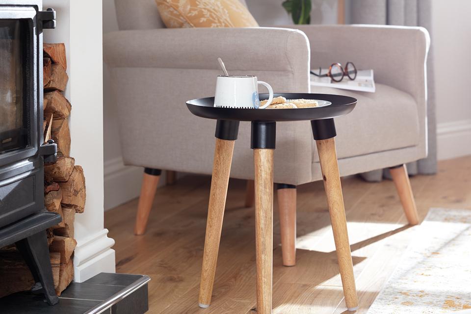 Image of small, round side table with wooden tapered legs.