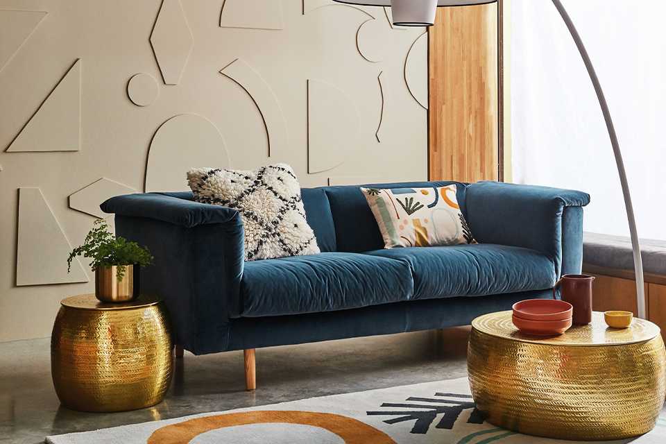 A living room with a glamorous coffee table, velvet sofa and floor lamp.