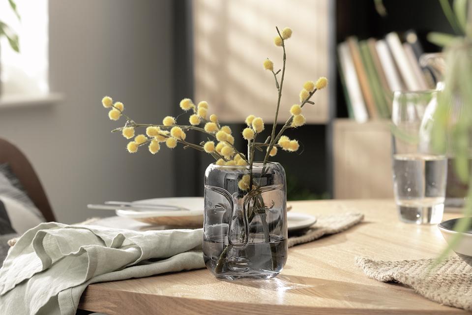 Grey-tinted vase on a dining table setting.