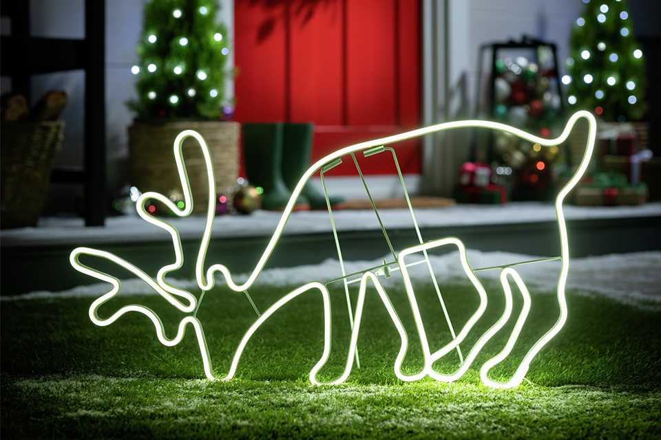 Reindeer neon light placed outside on a lawn. 