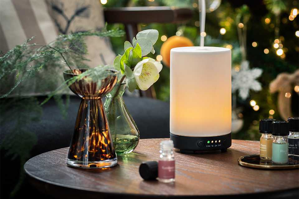 A table with vases, an electric diffuser, and bottles of diffuser refills. 