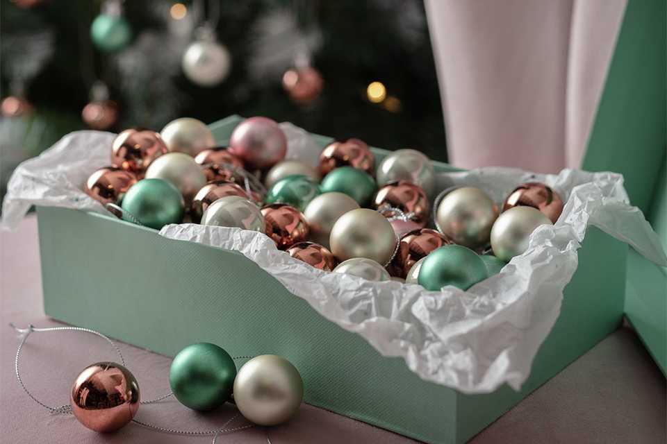 A box full of baubles in green, pink and silver colour. 