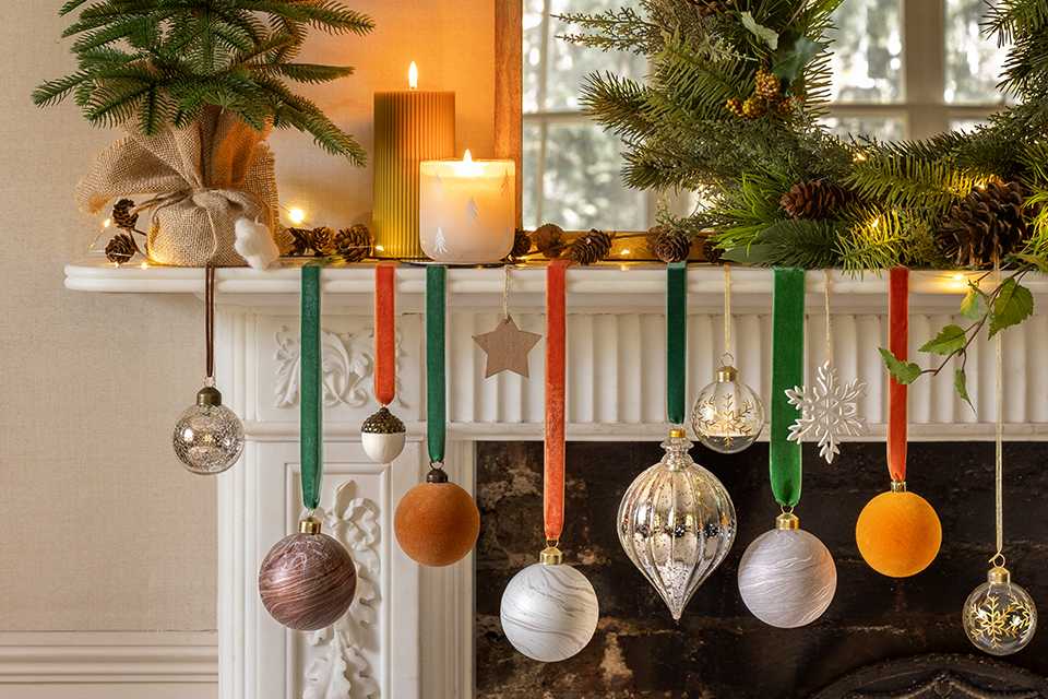 Candles, mini Christmas tree and a wreath on a fireplace mantel. 
