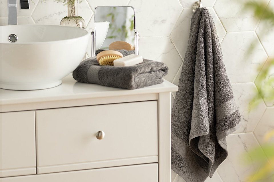 Bathroom sink and cupboard with towels and flannel on side.