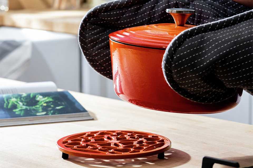Orange oven pot withstainless steel trivet.