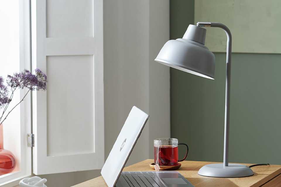 Grey office table lamp on table with laptop.