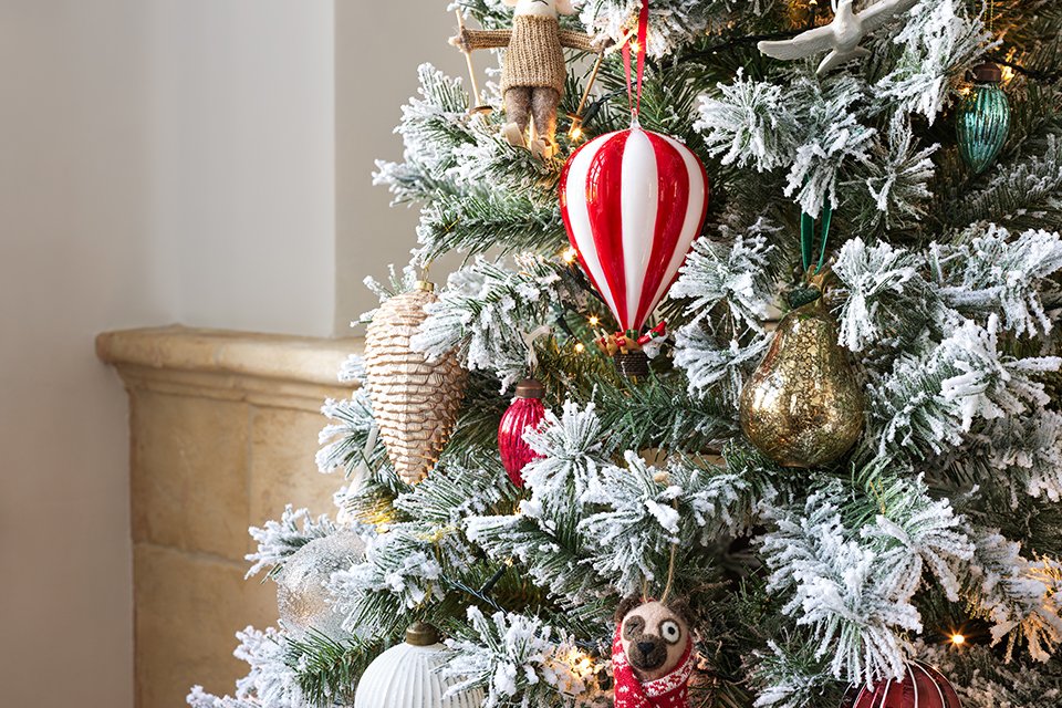 A Christmas tree decorated with red baubles in a house.