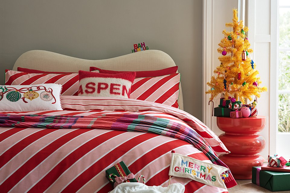 A bed made with red and white striped Christmas bedding.