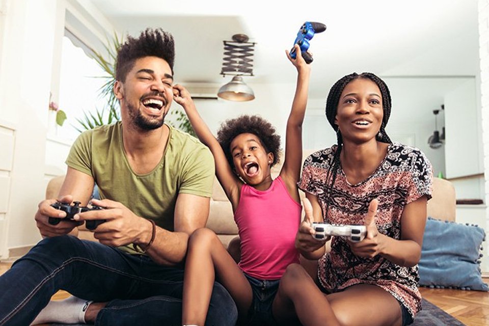 A young girl playing games on her gaming console with her parents.