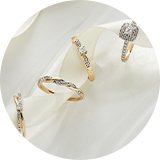 A set of rings with an off-white satin ribbon through them displayed on a white background.