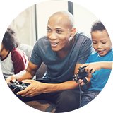 Two kids playing video games on consoles with their father.