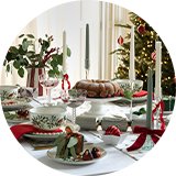 Candles, red ribbons, and little presents used to decorate a Christmas dinner table.