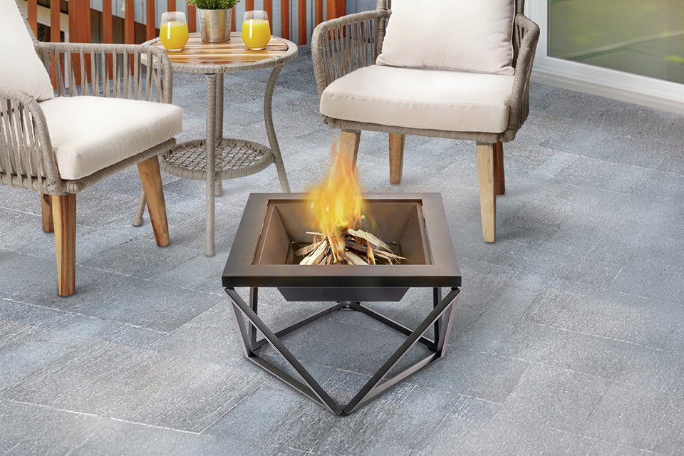 A Teamson Home wood burning fire pit being used outdoors on a patio.