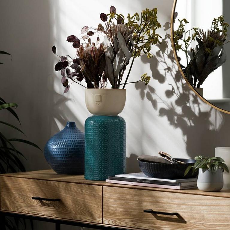 Image of a teal vase on a sideboard.