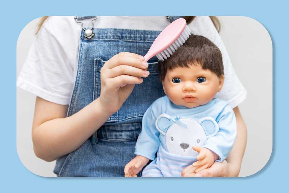 Child brushing the hair of a  44cm Tiny Treasures baby doll dressed in a blue outfit. 