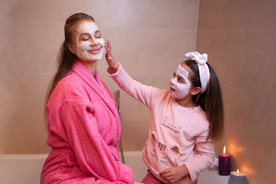 A mother and daughter having fun while doing a skincare routine.