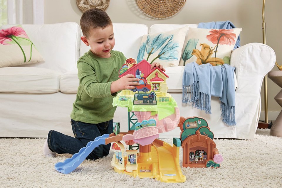 A boy playing with VTech Toot-Toot Drivers Bluey road trip playset.